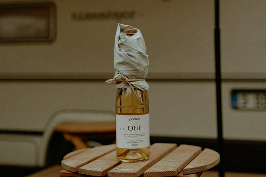 Vinflaska inlindad i en duk på ett campingbord