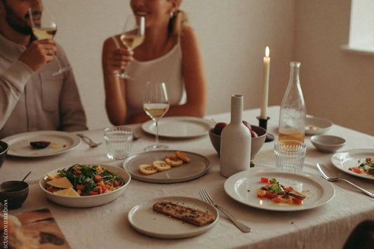 Vänner vid bordet med vitt vin och dukade tallrikar